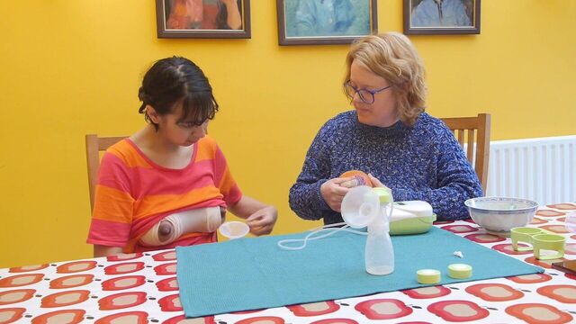 Old woman teaching young woman to pump breast milk